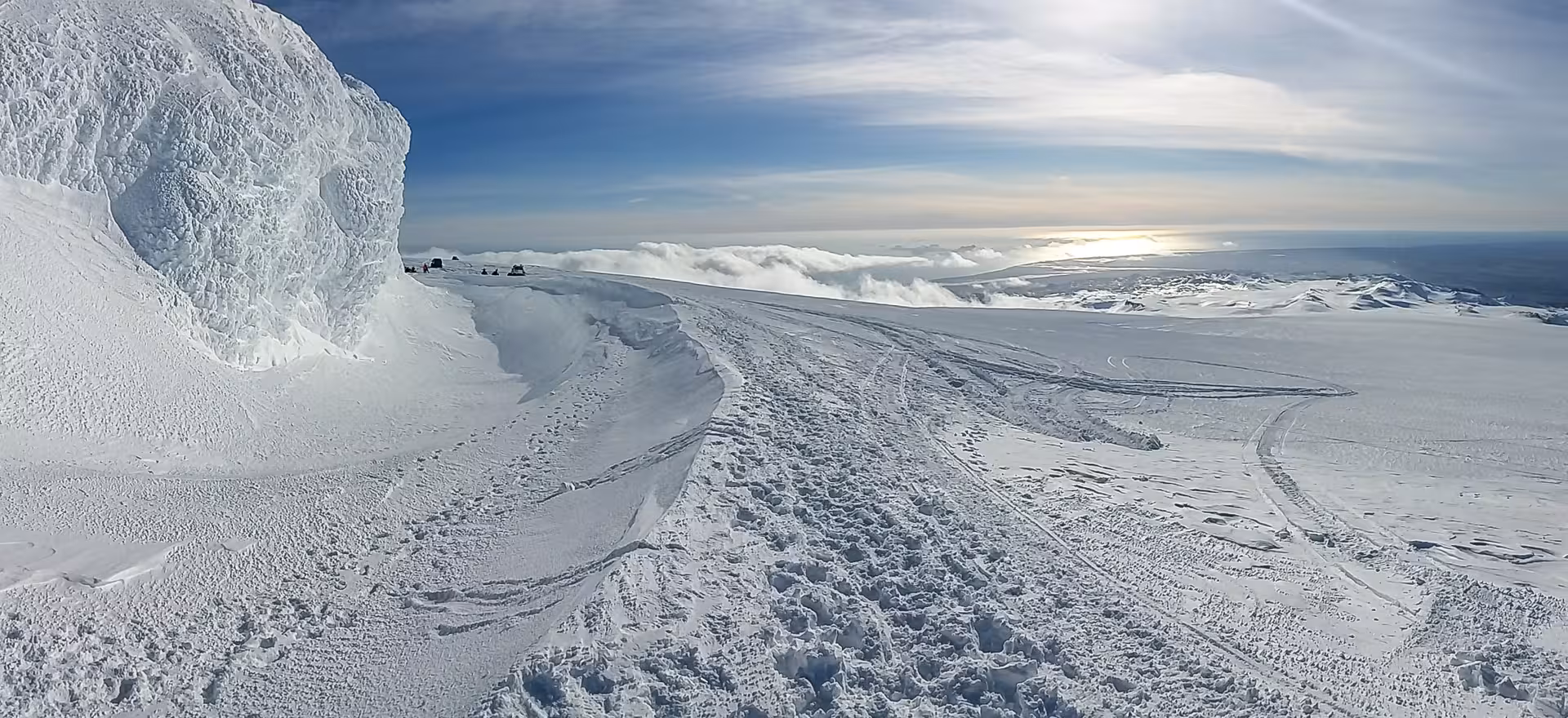 Panoramic view of snow-covered Eyjafjallajokull glacier with ice formations and snowmobile tracks in Iceland