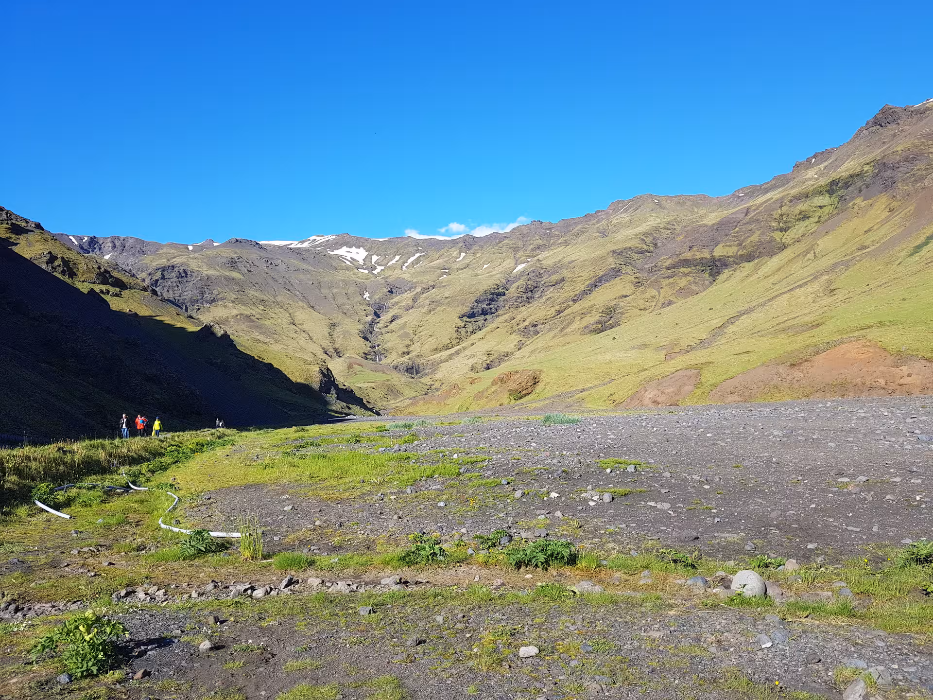 Green glacial valley leading to Eyjafjallajokull glacier summit with hikers on trail, Iceland