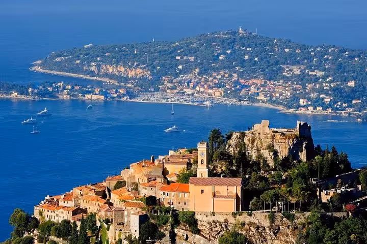 Aerial view of Eze village perched on cliffs above the French Riviera with Monaco coastline in background