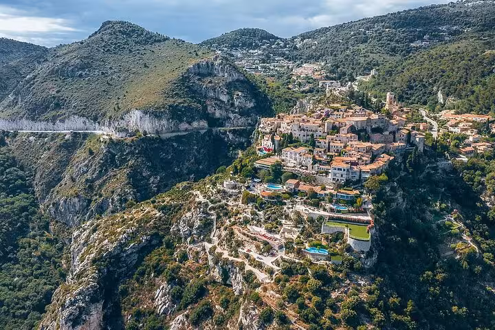 Aerial view of Eze medieval village perched on rocky cliffs with terracotta rooftops and lush green mountains