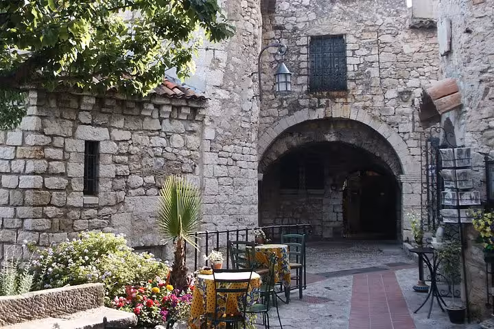 Medieval stone archway and outdoor café tables in Eze village, French Riviera
