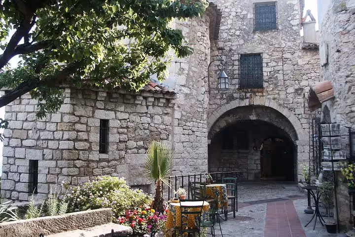 Medieval stone archway and courtyard with outdoor cafe seating in Eze village, French Riviera