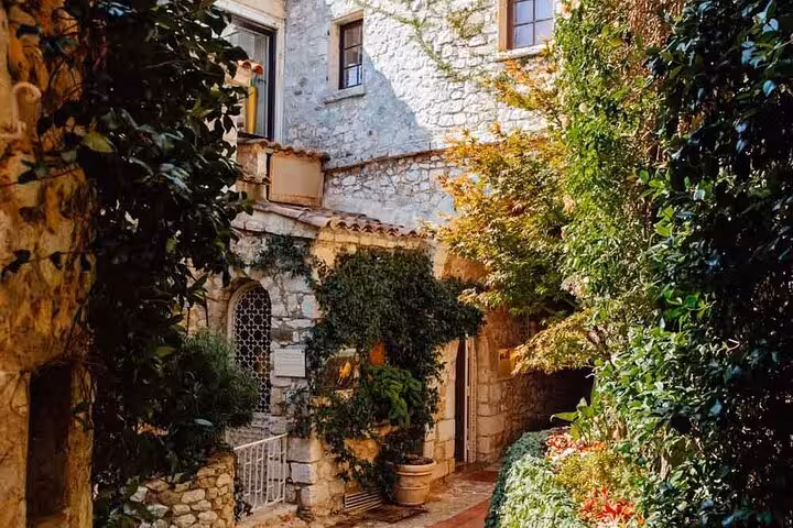 Stone courtyard with lush greenery and arched window in medieval village of Eze, French Riviera