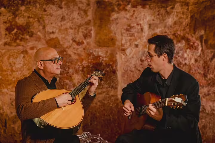 Two musicians passionately perform Fado with traditional Portuguese guitars in a cozy, rustic Lisbon venue.