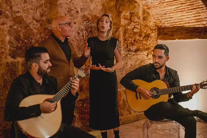 Musicians and singer perform traditional Fado in a cozy Lisbon venue, offering an authentic cultural experience with wine.