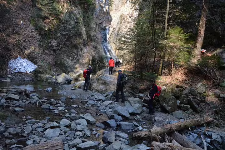 Hikers with backpacks exploring rocky canyon with waterfall on Fagaras hiking tour