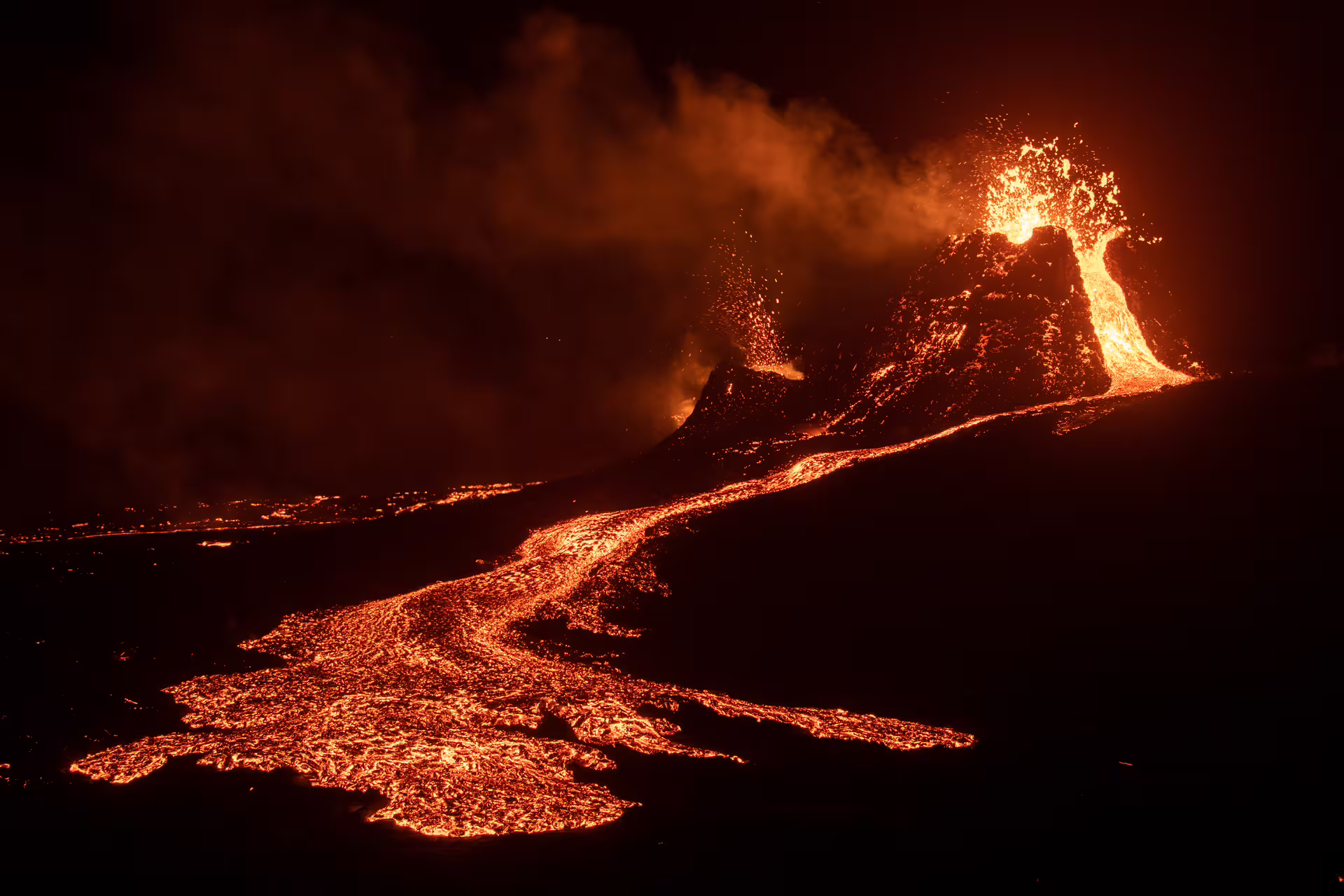 Glowing lava flow and erupting lava fountain at Fagradalsfjall volcano Iceland at night