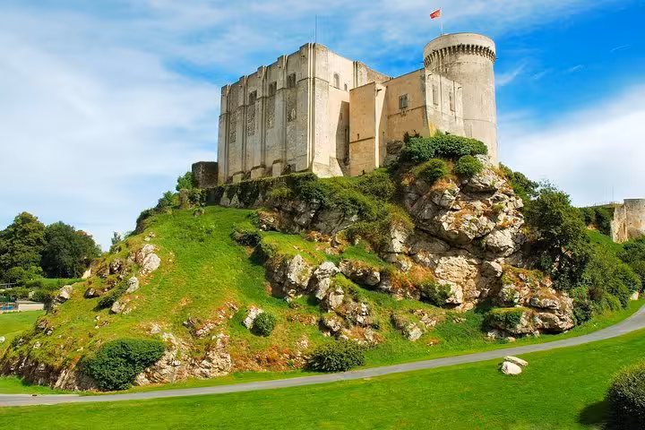 Falaise Castle perched on rocky hill with green lawns and blue sky, Normandy France