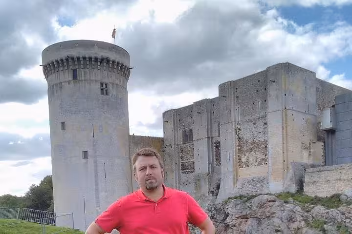 Man in red polo standing before Falaise Castle tower and keep, Normandy, France