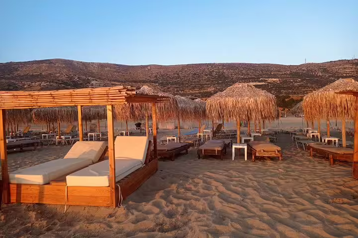 Luxurious sunbeds and thatched umbrellas on the sandy shores of Falasarna Beach at sunset, Crete.