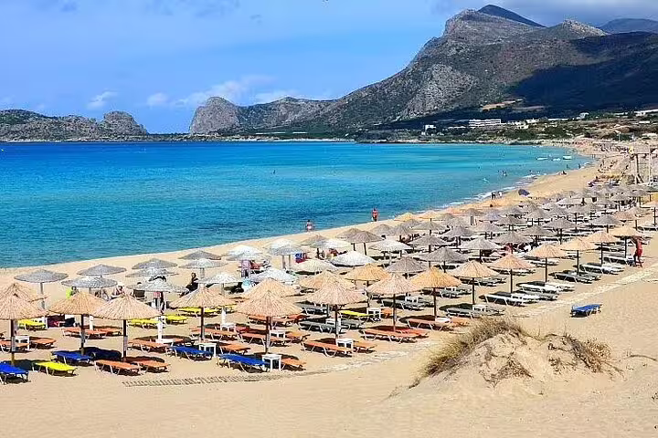 Relax on Falassarna Beach's golden sands with sun loungers and umbrellas, set against the backdrop of Crete's majestic mountains.