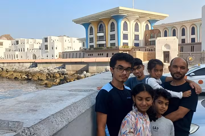 Family posing near Al Alam Palace waterfront during Muscat heritage evening walking tour in the old quarter