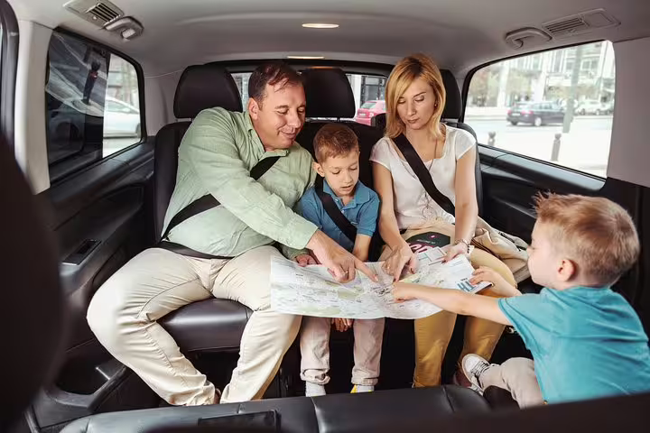 Family exploring Amsterdam on a private 2-hour sightseeing tour, studying a map inside a comfortable vehicle.