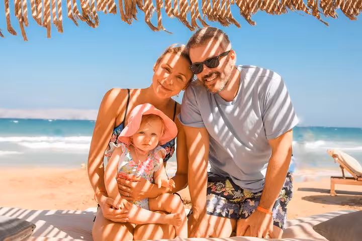 Family sitting under a beach umbrella in Heraklion, capturing joyful moments during a private photoshoot session.