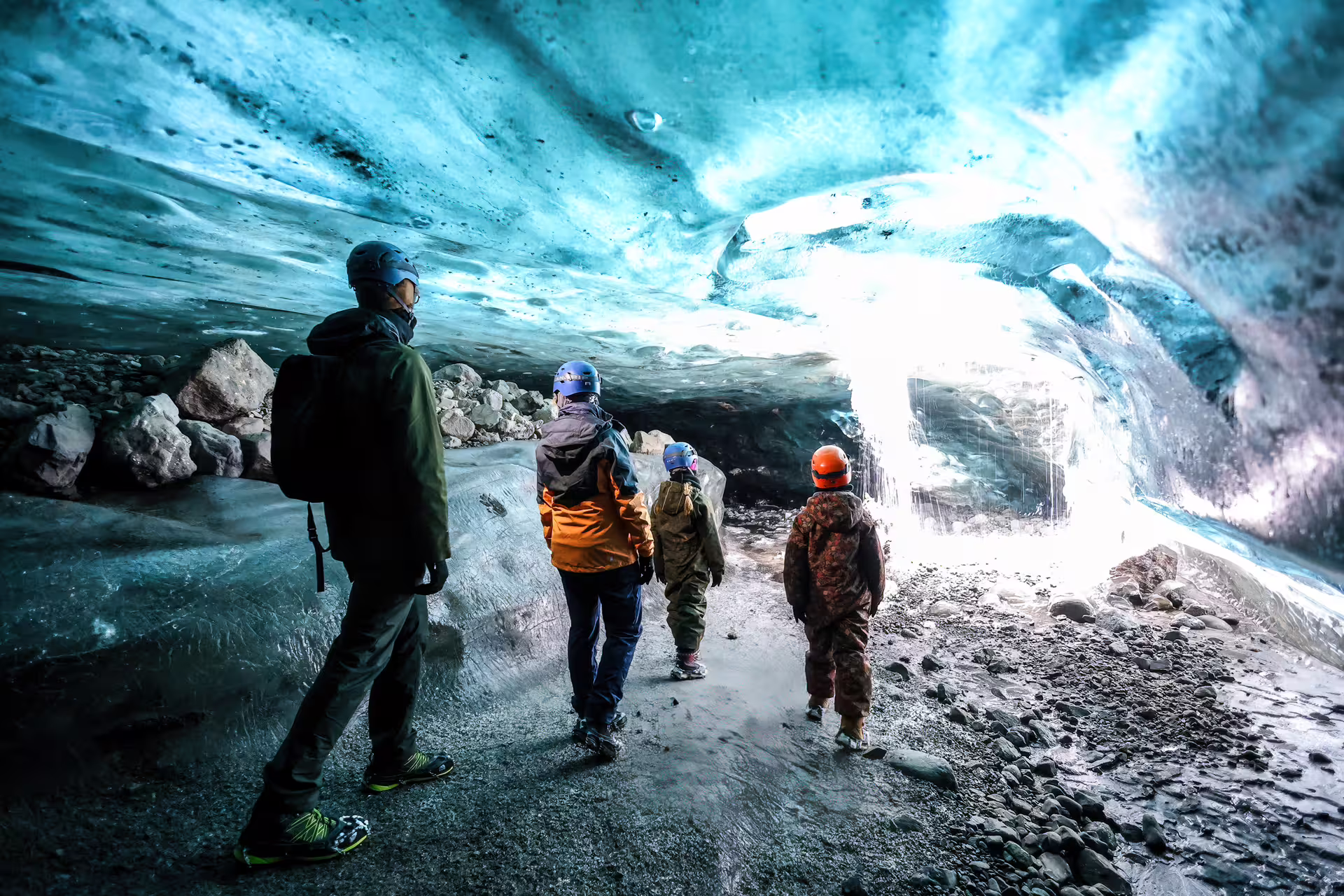 Family with helmets exploring a breathtaking blue ice cave on a guided Vatnajokull Glacier tour Iceland