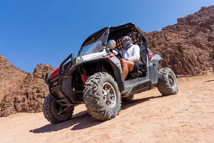 Off-road buggy climbing sandy canyon on family desert safari tour from Sharm El Sheikh in Sinai mountains