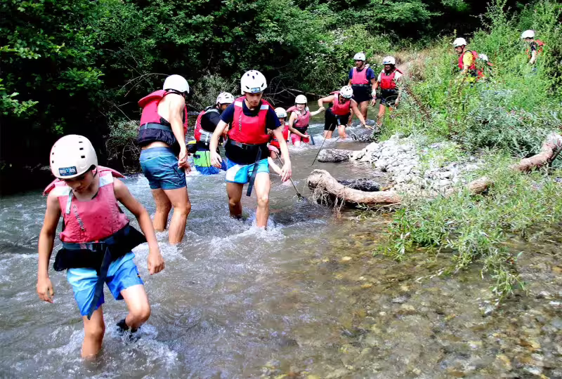 Family group canyoning in a shallow river in Pollino National Park, enjoying safe guided adventure near Altomonte