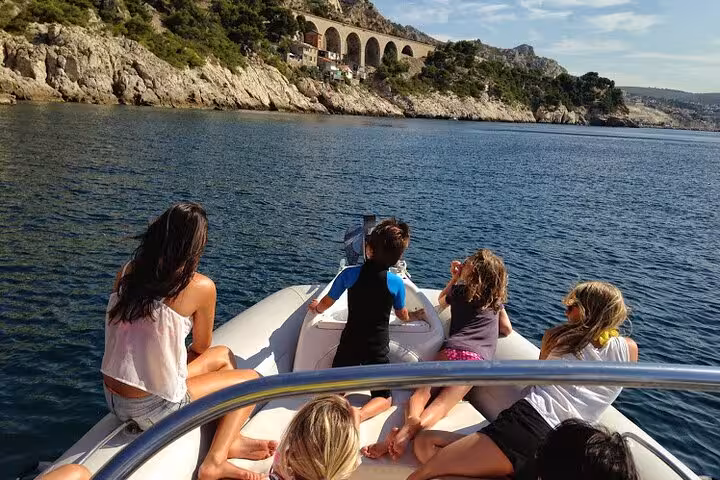 Family relaxing on boat facing rocky Calanques near Marseille during a full-day private catamaran cruise