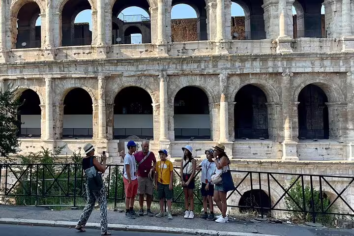 Family posing for a photo outside the Colosseum during an official guided tour of Rome’s Colosseum, Palatine Hill and Forum