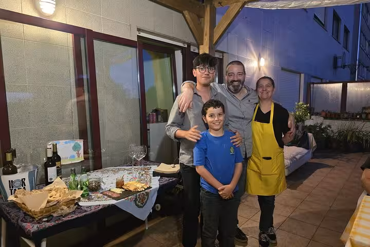 Family posing on a terrace with Portuguese cuisine set up for a cooking class experience.