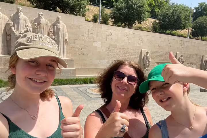 Family giving thumbs up at Geneva Reformation Wall on a fun scavenger hunt and city highlights walking tour