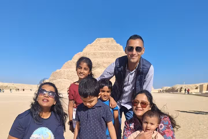 Family posing happily at the Saqqara Pyramid during a private Giza tour with Memphis and lunch included.
