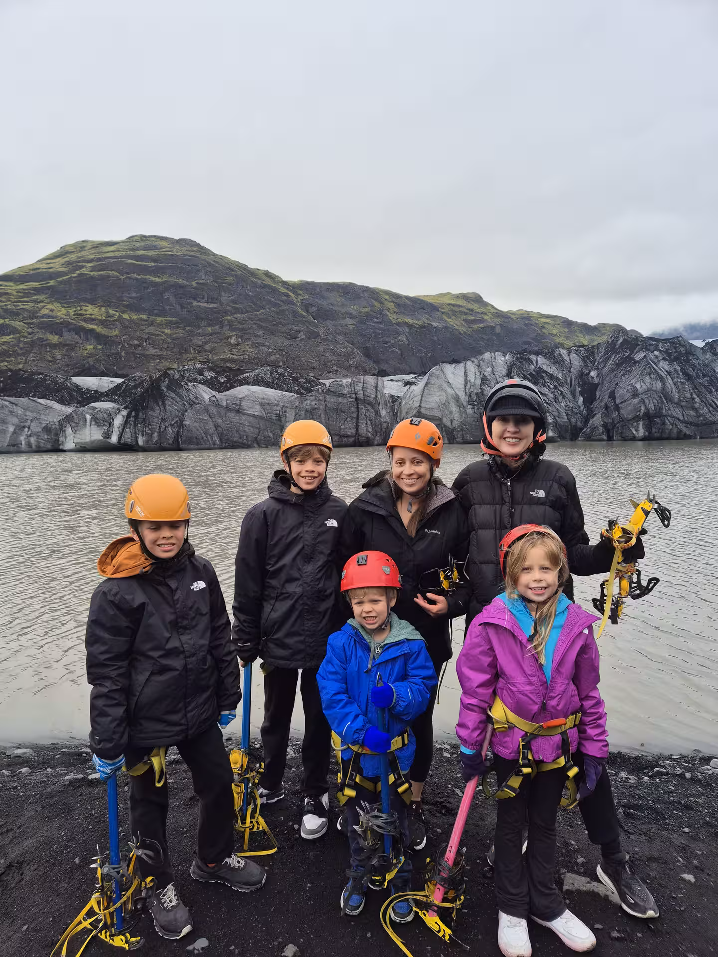 Family group with crampons and ice axes posing before glacier lagoon on Iceland South Coast tour