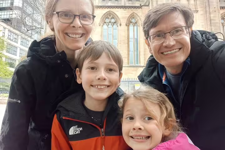 Family of four smiling together on Glasgow Ghost Hunt walking tour near historic cathedral