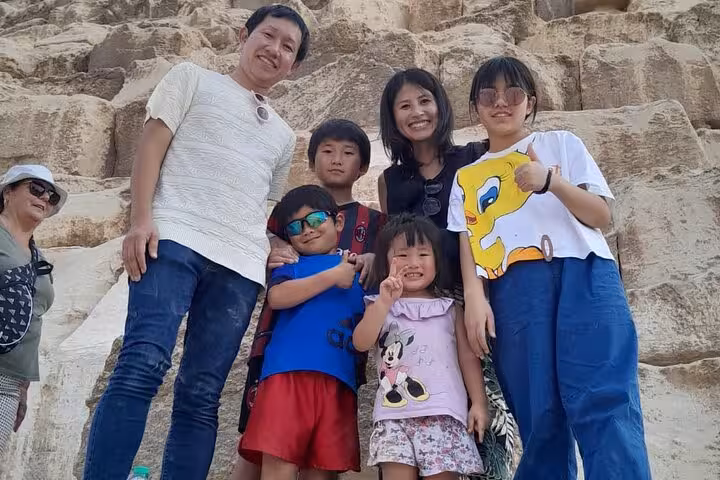 Family group photo by the Great Pyramid stones on a 3-day all-inclusive Cairo Pyramids tour in Giza