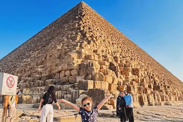 Family photo at the Great Pyramid of Giza on a Cairo private tour, with close-up limestone blocks and blue sky
