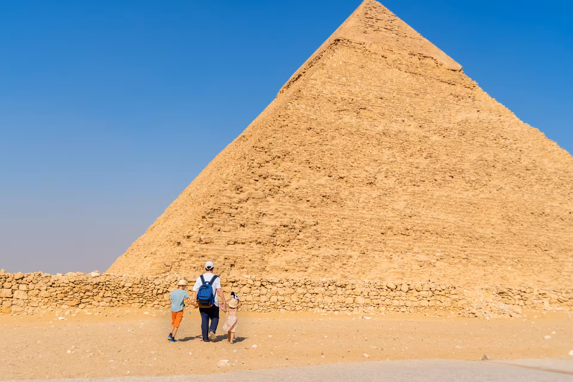 Family walking beside the Great Pyramid of Giza on a private day tour from Cairo to pyramids and Grand Egyptian Museum