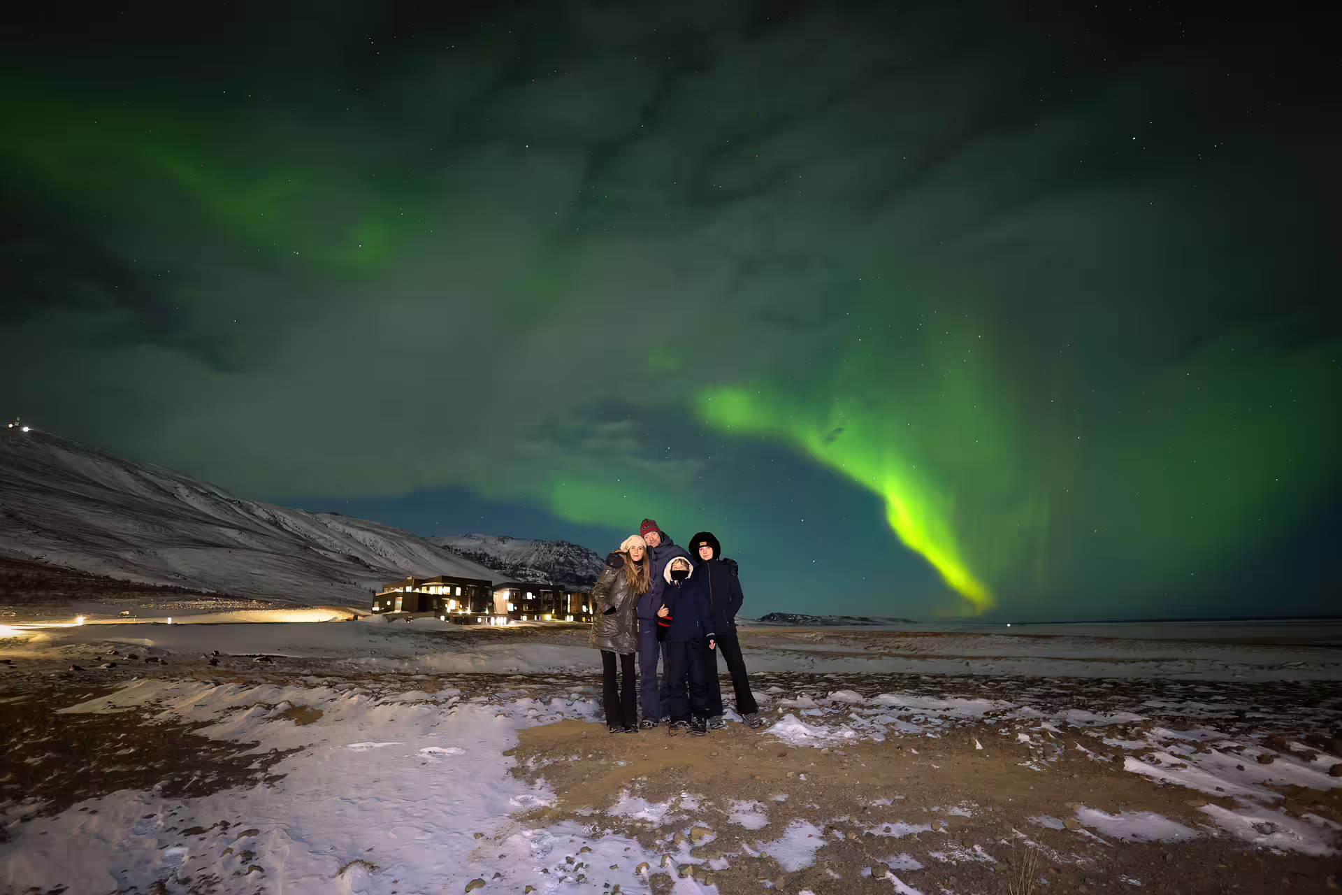 Family posing under vivid green northern lights in Iceland on a private aurora photography tour