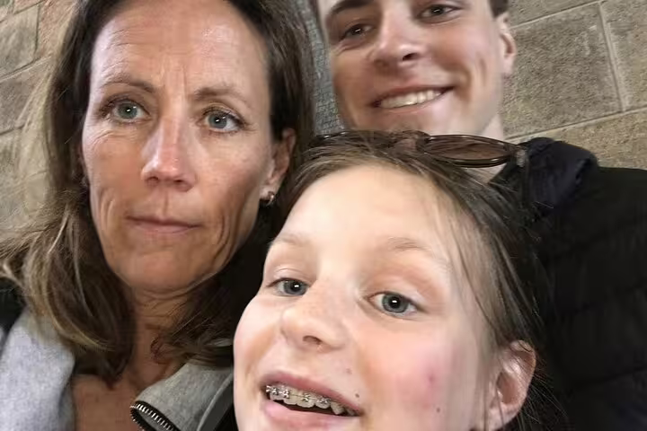 Woman, teenage girl with braces, and young man taking a selfie together indoors