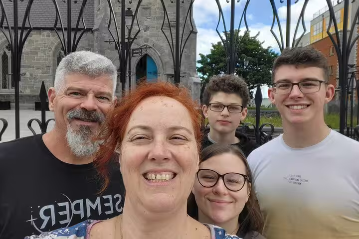 Family of five smiling together outside historic Dublin church gates on a guided walking tour