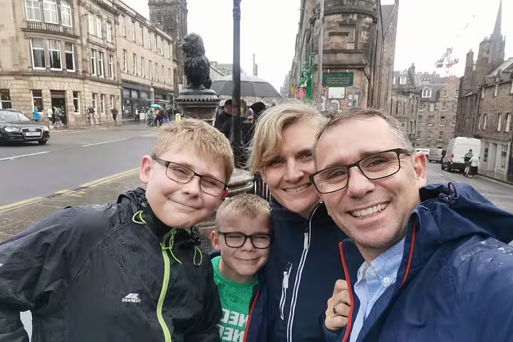 Family taking a selfie on a rainy Edinburgh Royal Mile street during a haunted walking tour