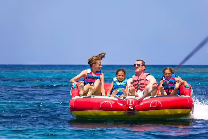 Family riding red inflatable tube on Red Sea, VIP boat day trip from Hurghada to Dolphin House