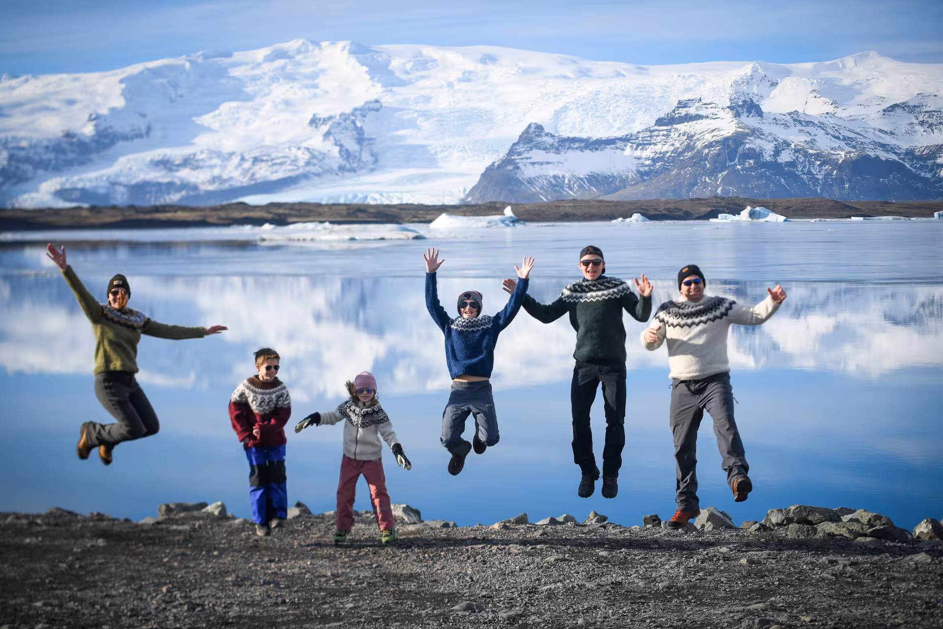 Excited family jumping near Jokulsarlon glacier lagoon on Iceland full-day glacier hike tour