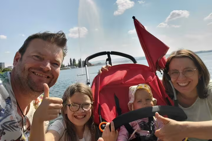 Family selfie by Lake Zug with stroller, enjoying Zug scavenger hunt self-guided walking tour sights