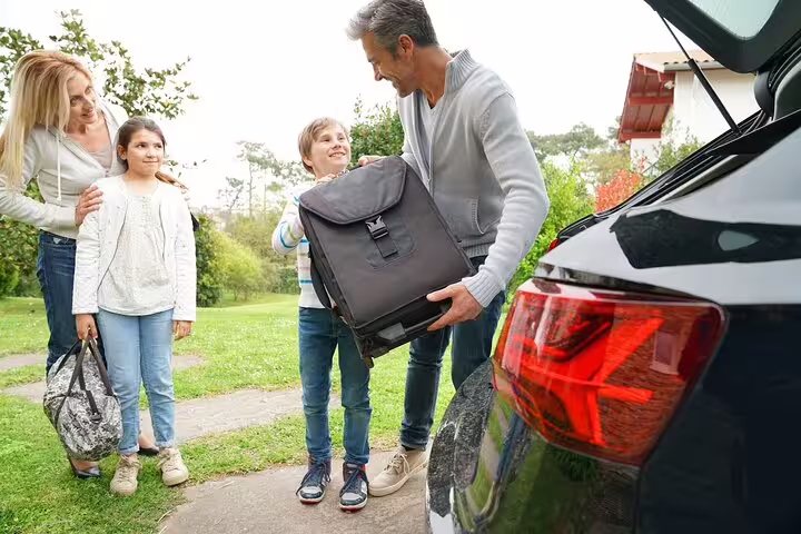 Family loading luggage into car trunk for airport transfer trip