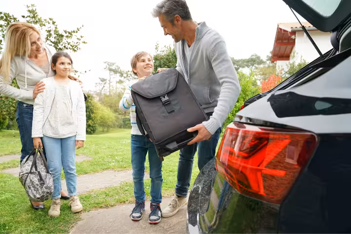Family loading luggage into car trunk for airport transfer trip