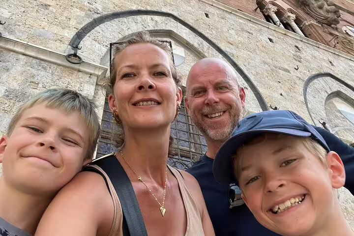 Family of four smiling together on a medieval walking tour in Siena, Italy