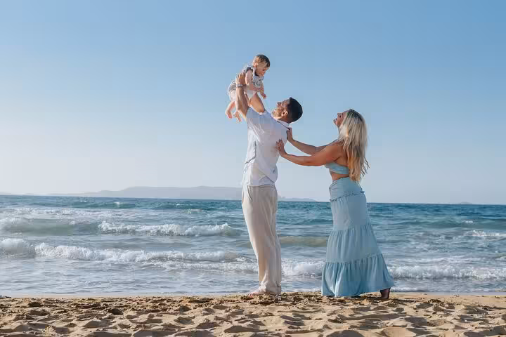 Happy family playing on Analipsi beach with clear blue skies and waves, ideal for capturing special moments in a private photoshoot.