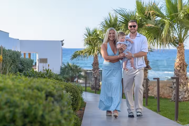Happy family walking along a picturesque path near the sea in Analipsi, perfect setting for a memorable photoshoot.