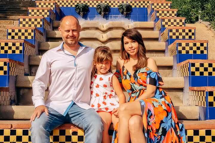 Family enjoys professional photoshoot on colorful Gaudí-inspired mosaic steps in Barcelona, perfect for timeless vacation memories.