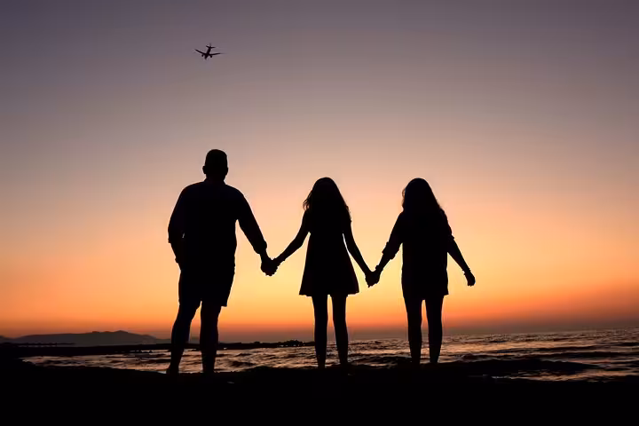 Family of three holds hands at Hersonissos beach during sunset, creating beautiful silhouette for a memorable photoshoot.