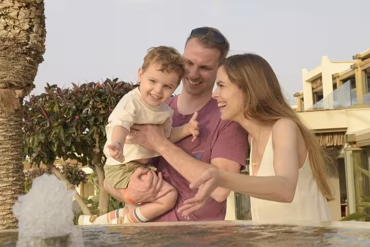 Happy family enjoying a private photoshoot by a fountain in sunny Hersonissos, perfect for capturing memorable moments.
