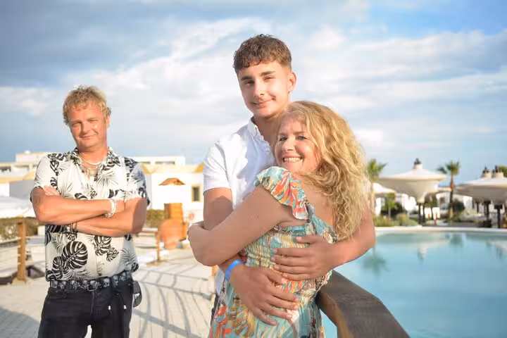 Family enjoying a private photoshoot by a pool in Malia, capturing joyful moments under a bright blue sky.