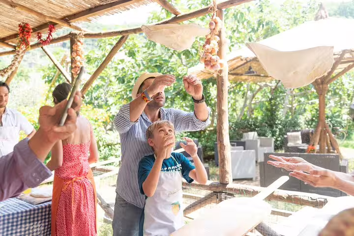 Family stretching pizza dough at a local farm pizza school with wine and limoncello tasting in Italy