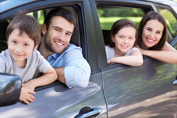 Happy family leaning out of car windows smiling during a private transfer ride