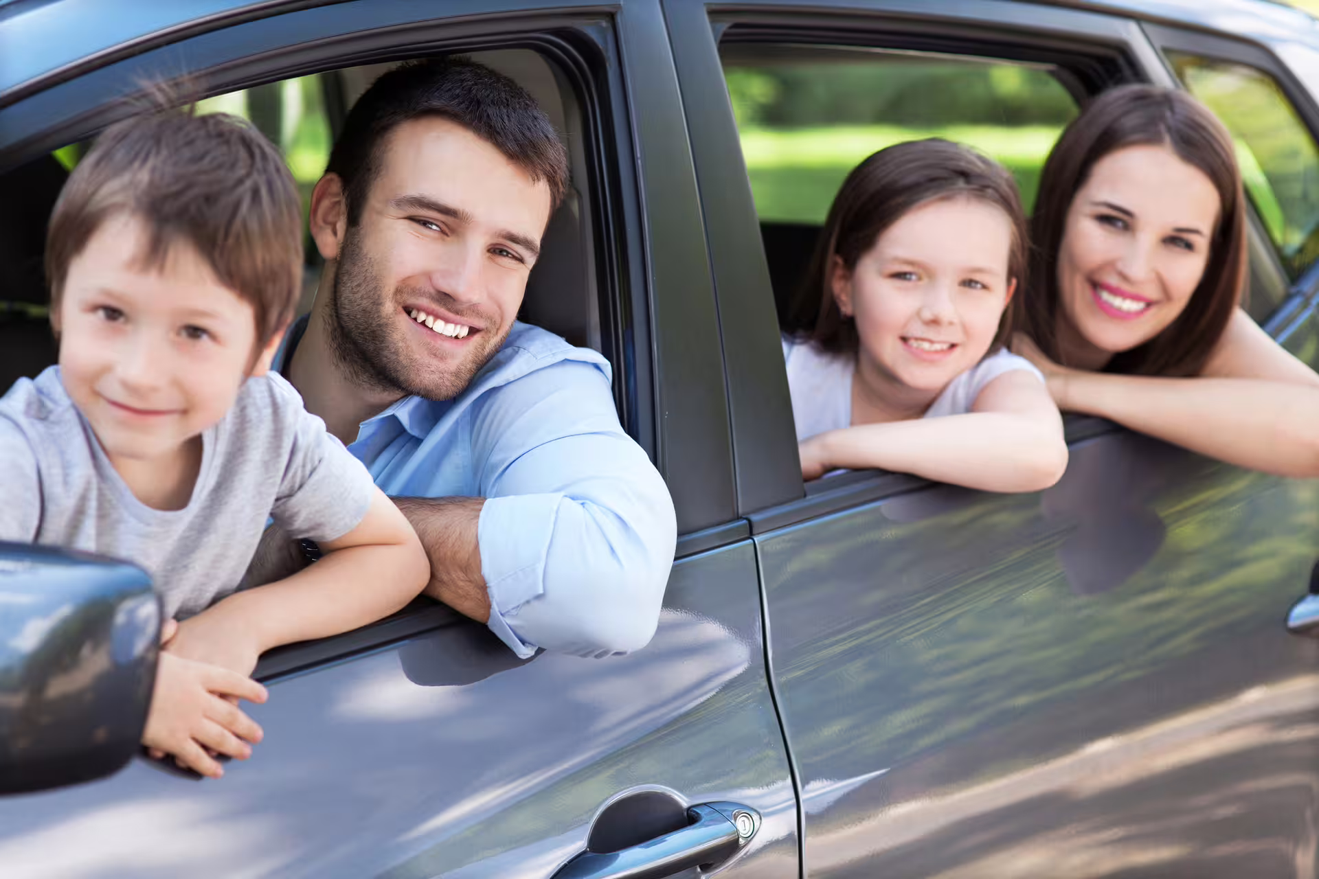 Happy family leaning out of car windows smiling during a private transfer ride